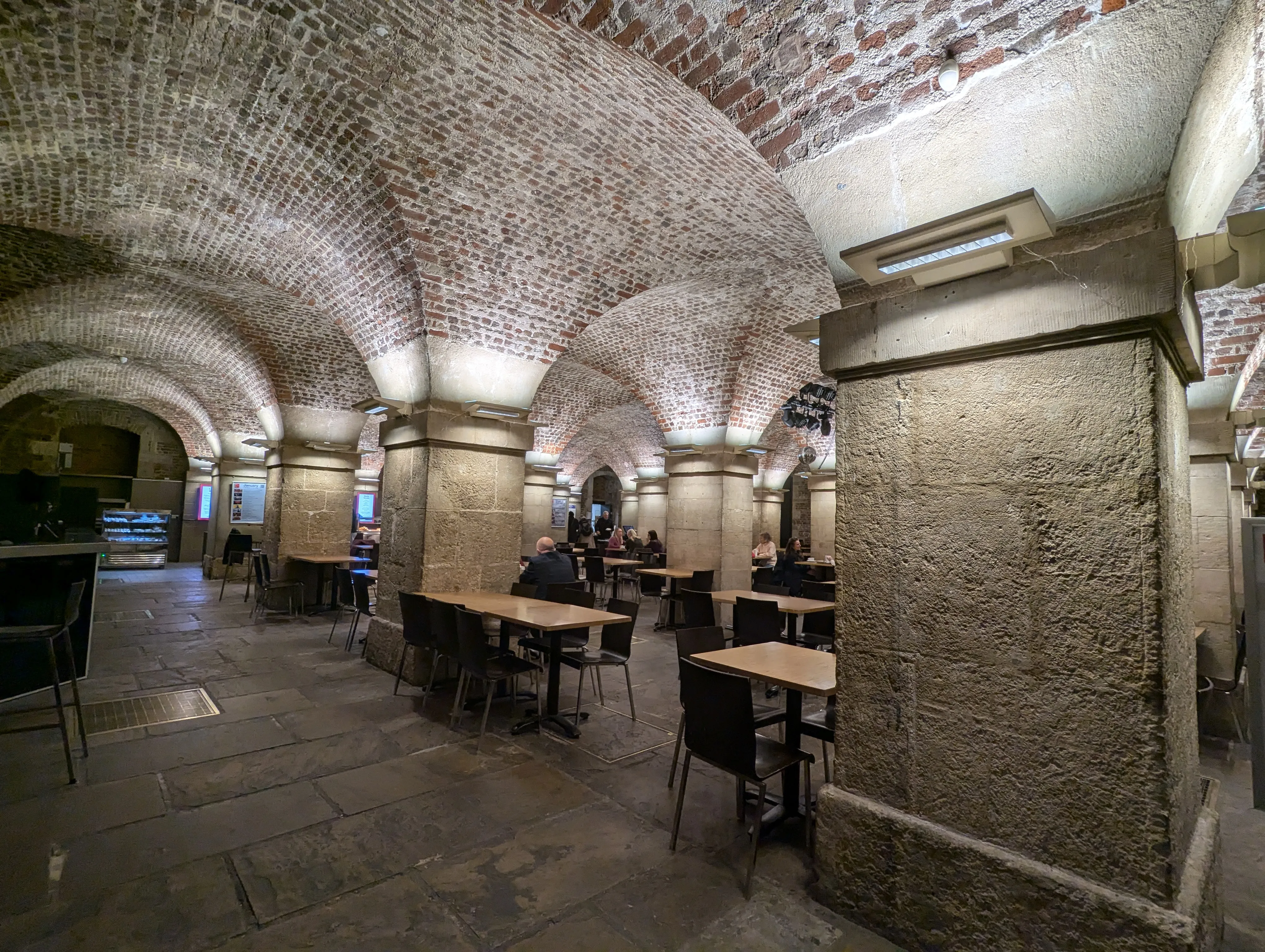 Underground, lots of pillars, some tables with people.